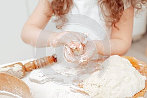 Food preparations. Little girl wearing an apron in the kitchen. Mixing dough to make cookies. Baking ingredients for shortcrust