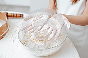 Food preparations. Mixing dough to make cookies. Close up of girl's hands has covered in flour