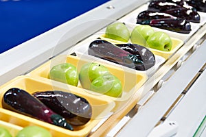 Food products apples and eggplant in plastic pack on conveyor