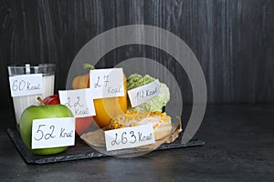 Food products with calorific value tags on black table, space for text. Weight loss concept photo