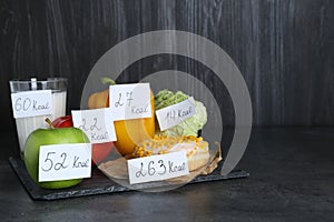 Food products with calorific value tags on black table, space for text. Weight loss concept