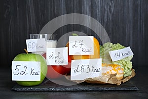 Food products with calorific value tags on black table. Weight loss concept