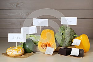 Food products with calorific value tags on wooden table. Weight loss concept photo