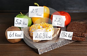Food products with calorific value tags on wooden table. Weight loss concept photo