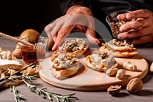 Food recipe background. chef preparing delicious bruschettas with brie camembert cheese, pear nuts and rosemary, New Years Eve or