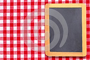 Food recipe template. Empty wooden black board on a red white checkered tablecloth. For your food and product display montage.