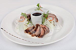 Sliced pork. Cutting meat with sauce. Baked meat with sauce on a white plate. photo