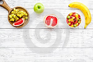 Food rich by vitamins and fiber. Healthy food. Fruit salad near fresh fruits on white wooden background top view copy