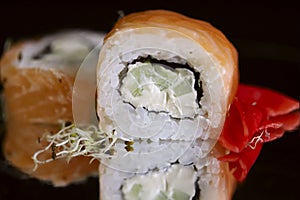 Food. Rolls Philadelphia on a black background on a mirror surface.