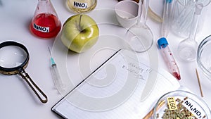 Food saferty lab. View of fresh ripe apple with test tubes and tools on table in research lab. Concept of genetic