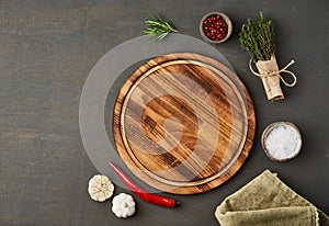 Food seasoning background. Menu, recipe, mock up. Round wooden cutting board on dark backdrop