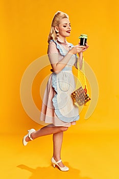 Food shopping. Portrait of beautiful young girl with stylish hairstyle posing against yellow studio background. Concept