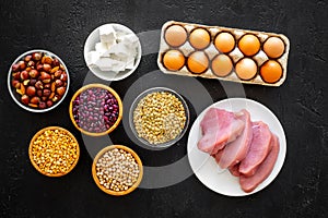 Food for sportsmen. Legumes, nuts, low-fat cheese, meet, eggs on black background top view