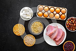 Food for sportsmen. Legumes, nuts, low-fat cheese, meet, eggs on black background top view