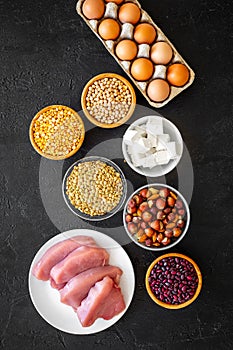 Food for sportsmen. Legumes, nuts, low-fat cheese, meet, eggs on black background top view