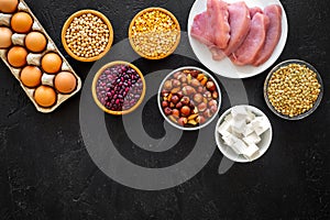 Food for sportsmen. Legumes, nuts, low-fat cheese, meet, eggs on black background top view copy space