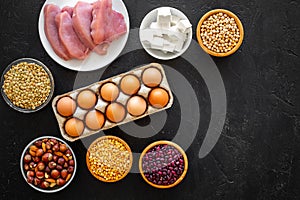 Food for sportsmen. Legumes, nuts, low-fat cheese, meet, eggs on black background top view copy space