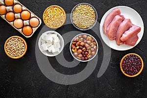 Food for sportsmen. Legumes, nuts, low-fat cheese, meet, eggs on black background top view copy space