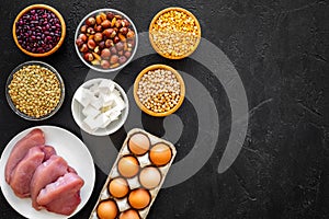 Food for sportsmen. Legumes, nuts, low-fat cheese, meet, eggs on black background top view copy space