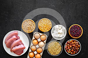 Food for sportsmen. Legumes, nuts, low-fat cheese, meet, eggs on black background top view copy space