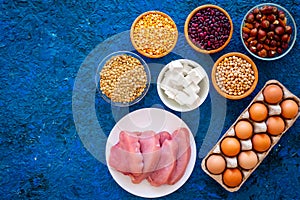 Food for sportsmen. Legumes, nuts, low-fat cheese, meet, eggs on blue background top view copy space