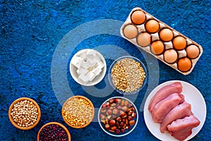 Food for sportsmen. Legumes, nuts, low-fat cheese, meet, eggs on blue background top view copy space