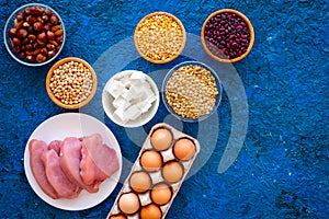 Food for sportsmen. Legumes, nuts, low-fat cheese, meet, eggs on blue background top view copy space