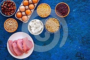 Food for sportsmen. Legumes, nuts, low-fat cheese, meet, eggs on blue background top view copy space