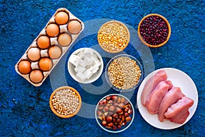 Food for sportsmen. Legumes, nuts, low-fat cheese, meet, eggs on blue table top view