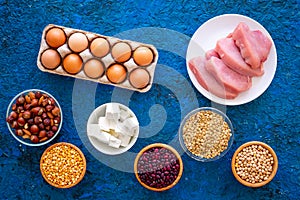 Food for sportsmen. Legumes, nuts, low-fat cheese, meet, eggs on blue table top view