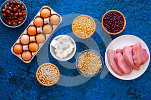 Food for sportsmen. Legumes, nuts, low-fat cheese, meet, eggs on blue table top view