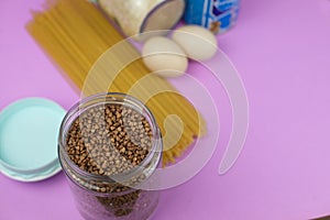 Food stock for quarantine isolation period on purple background. Rice, egg, canned food, buckwheat, spaghetti. Food delivery,