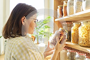 Food storage in pantry, woman holding jar of dry sun-dried apples in hand