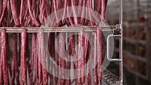 Food storage, warehouse. Meat products, sausages hanging on racks in a meat warehouse, freezer.