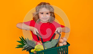 Food store. Child with hopping basket, isolated on yellow background. Child with shopping basket and grocery. Kids