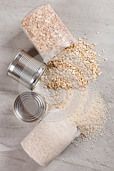Food supplies, jars of oatmeal and canned rice, on a stone countertop, a view from above