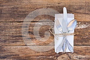 Place setting with cutlery and napkin on wooden table background