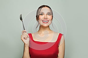 Food temptation. Beautiful young happy woman with empty fork impatiently on white background