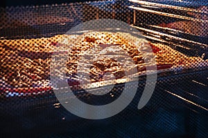 Food with tomatoes and cheese is baked in the oven. Food through the glass closed door of the oven