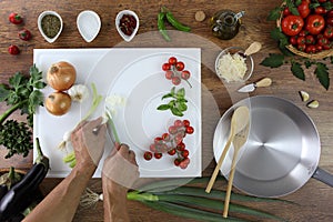 Food top view, hands cutting green onion on white chopping board