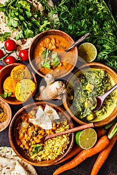 Food traditional Indian cuisine. Dal, palak paneer, curry, rice, chapati, chutney in wooden bowls on dark background