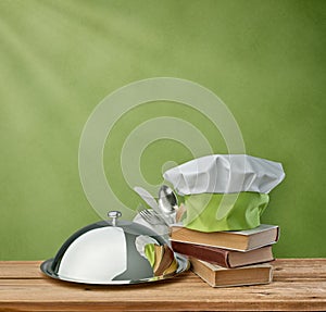 Food tray, cap chef and cookbook on a green vintage background