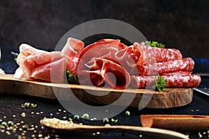 Food tray with delicious salami, coppa, crudo and herbs. Meat platter with selection on rustic table