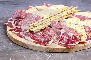 Food Tray With Delicious Salami Pieces of Sliced Ham and Crackers and Bread Sticks Meat Plate