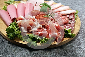 Food tray with delicious salami, pieces of sliced ham, sausage a