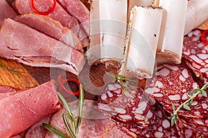 Food tray with delicious salami, pieces of sliced ham, sausage. Cutting sausage and cured meat on a celebratory table.