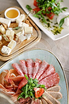 Food tray with delicious salami, pieces of sliced ham, sausage. Cutting sausage and cured meat on a celebratory table.