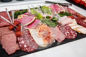 Food tray with delicious salami, pieces of sliced ham, sausage, salad - Meat platter with selection