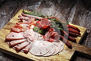 Food tray with delicious salami, pieces of sliced ham, sausage and salad. Meat platter selection