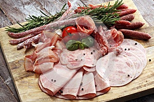 Food tray with delicious salami, pieces of sliced ham, sausage and salad. Meat platter selection